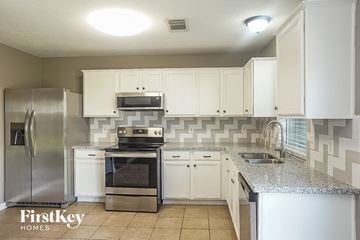 Cypress house for rent - a kitchen with white cabinets and stainless steel appliances
