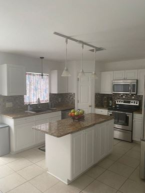 Sanford house for rent - a kitchen with white cabinets and a marble counter top