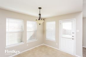 Fort Worth house for rent - A room with a chandelier, two windows with blinds, and a door.