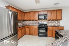 Fort Worth house for rent - A kitchen with wooden cabinets and a stainless steel refrigerator.