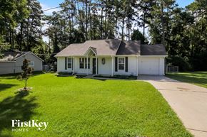 Conroe house for rent - a white house with a lawn and trees in front of it