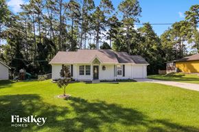 Conroe house for rent - a small white house with a grassy yard and trees