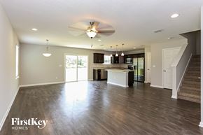 Jacksonville house for rent - an empty living room and kitchen with a ceiling fan