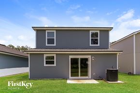 Jacksonville house for rent - the exterior of a gray house with a lawn and a trash can
