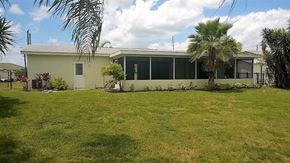 Palmetto house for rent - a house with a lawn and palm trees in front of it