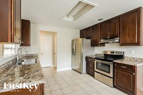 San Antonio house for rent - A kitchen with a stove top oven and a refrigerator.