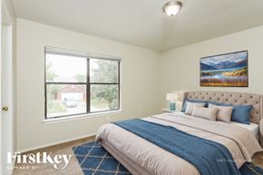 San Antonio house for rent - A bedroom with a large bed and a painting of a lake on the wall.