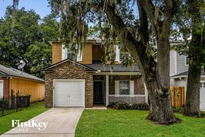 Jacksonville house for rent - a brick house with a white garage door and a large tree