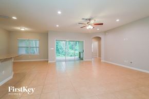 St. Johns house for rent - A spacious room with a ceiling fan and sliding glass doors leading to a garden.