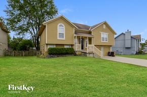 Raymore house for rent - a yellow house with a yard in front of it