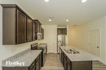 Winston Salem house for rent - A kitchen with dark brown cabinets and a granite countertop.