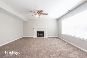 Indianapolis house for rent - A spacious room with a fireplace and a ceiling fan.