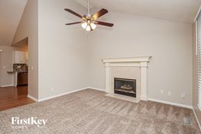 Kansas City house for rent - A living room with a fireplace and a ceiling fan.