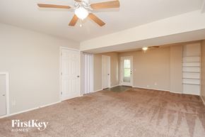 Kansas City house for rent - A spacious room with a ceiling fan and beige carpeting.