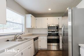 Largo house for rent - a kitchen with white cabinets and stainless steel appliances and a window