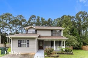 Loganville house for rent - a small gray house with a porch and a lawn and trees