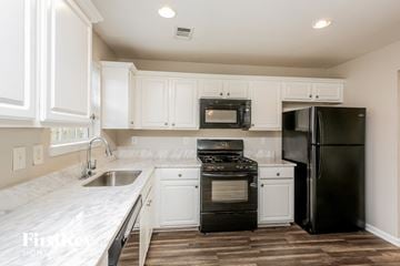 Pendergrass house for rent - a kitchen with white cabinets and black appliances