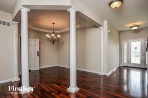 St Charles house for rent - an empty living room with pillars and a wood floor