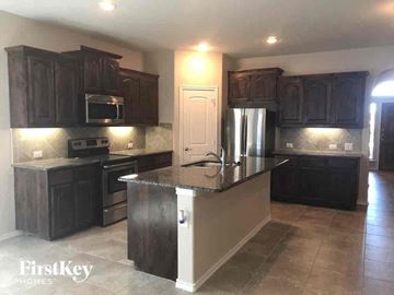 Weatherford house for rent - A kitchen with dark wood cabinets and a granite countertop.