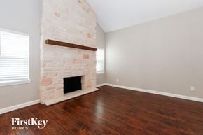 Plano house for rent - a living room with a stone fireplace and wooden floors