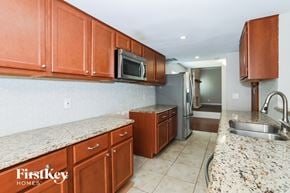 Plano house for rent - a kitchen with granite counter tops and wooden cabinets