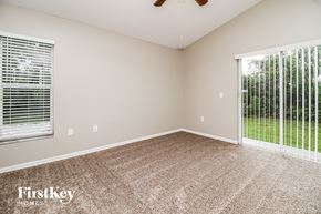 Deltona house for rent - a spacious living room with a large window and carpeted flooring