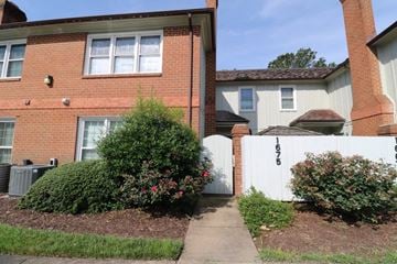 Virginia Beach house for rent - A red brick house with a white fence and a small garden in front.