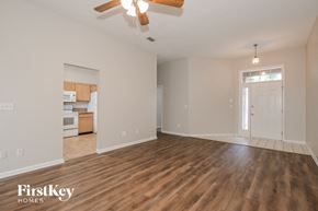 Jacksonville house for rent - an empty living room and kitchen with wood flooring and a ceiling fan