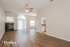 Jacksonville house for rent - an empty living room with a fireplace and a ceiling fan