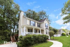 Snellville house for rent - A house with a white facade and a brown roof is surrounded by greenery.