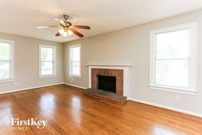 Snellville house for rent - A room with a fireplace and a ceiling fan.