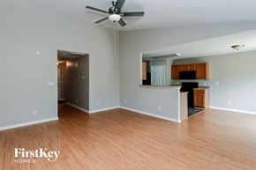 Charlotte house for rent - an empty living room and kitchen with wood floors and a ceiling fan