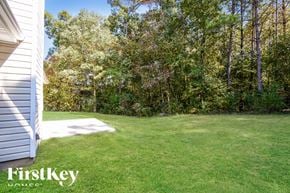 Ellenwood house for rent - a backyard with green grass and trees and a white house