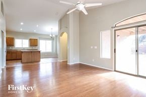 Tucson house for rent - an empty living room with a kitchen and a ceiling fan