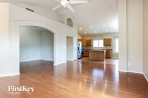 Tucson house for rent - an empty living room and kitchen with wood floors and a ceiling fan