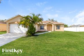 Port St Lucie house for rent - a house with a lawn and palm tree in front of it