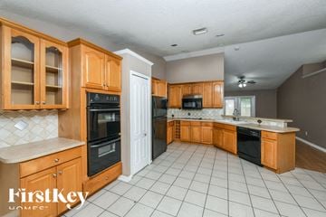 Orlando house for rent - A kitchen with wooden cabinets and black appliances.