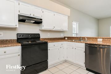Apopka house for rent - A kitchen with a black stove top oven and a stainless steel dishwasher.