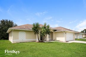 Lehigh Acres house for rent - a beige house with a palm tree in the yard