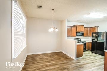 Lawrenceville house for rent - a kitchen and living room with wood flooring and a black refrigerator