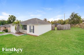Orange City house for rent - a backyard with a small white house and a green lawn