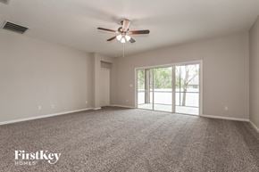 Jacksonville house for rent - A spacious room with a ceiling fan and sliding glass doors leading to a balcony.