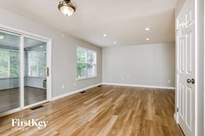 O'fallon house for rent - an empty living room with a hardwood floor and a door to a bedroom