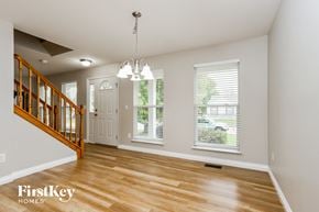 O'fallon house for rent - an empty living room with a staircase and a white door and windows