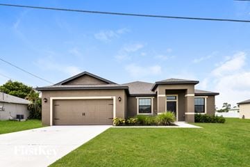 Cape Coral house for rent - a house with a garage door in front of a lawn