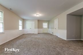 Stone Mountain house for rent - A spacious room with a carpeted floor and white walls, with a FirstKey Homes logo in the corner.