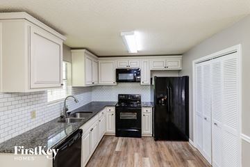 Clermont house for rent - a kitchen with white cabinets and black appliances