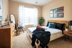 Council Bluffs apartment for rent - A bedroom with a bed, chair, and a plant.