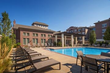 Omaha apartment for rent - A pool surrounded by lounge chairs and a building in the background.