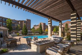 Omaha apartment for rent - A patio with a pool and chairs under a wooden roof.